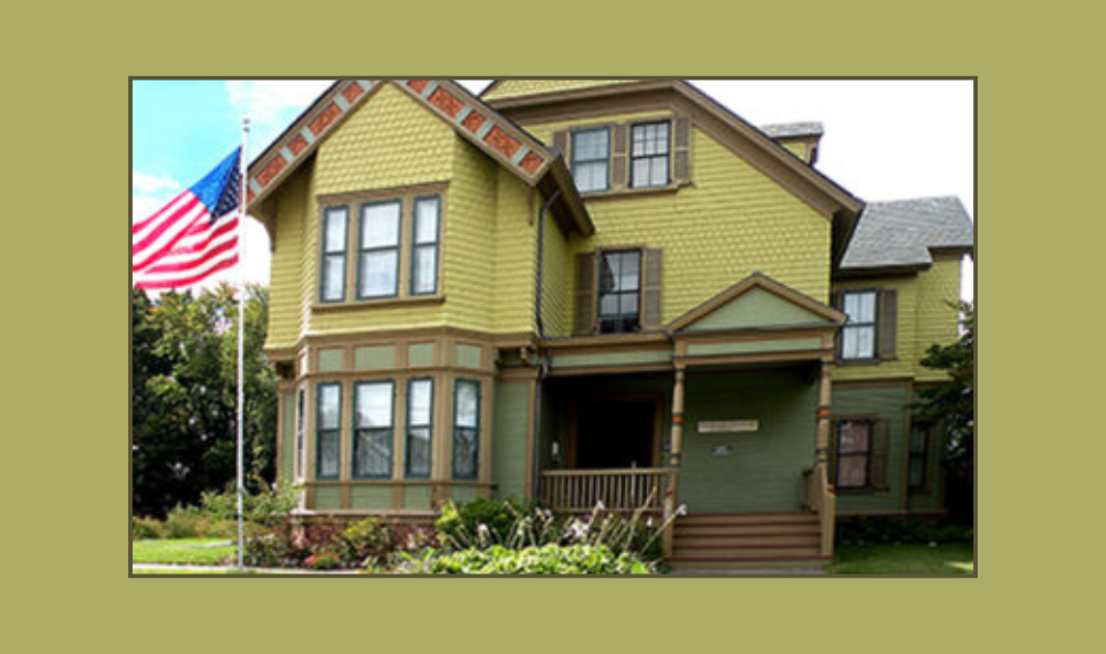 Image of the Hedrick House, home of the Peekskill Museum. Building is a green Victorian with an American flag in the left foreground